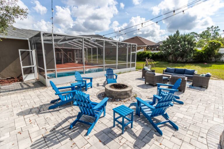 After: Michaels House backyard fire pit patio with blue Adirondack chairs beside the screened pool, Hernando County FL